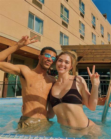 a man and woman standing in a pool with their hands up to the camera ...