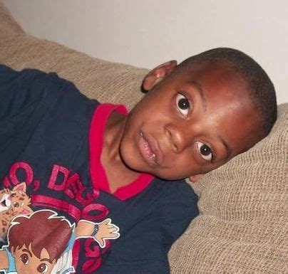 a young boy sitting on top of a couch wearing a t - shirt with cartoon ...