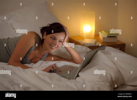 Bedroom evening - woman with laptop lying down in bed Stock Photo - Alamy