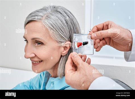 Invisible In-The-Canal hearing aids. doctor demonstrates display stand ...