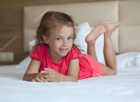 Cheerful little girl lying on the bed. — Stock Photo © yykkaa #6893947