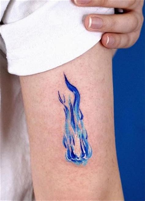 a woman's arm with a blue fire tattoo on it