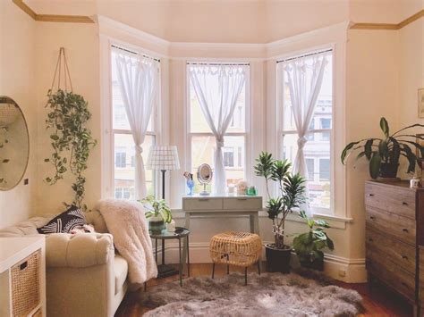 a living room filled with furniture and lots of plants on the window ...