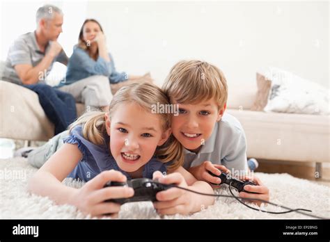 Cheerful children playing video games with their parents on the Stock ...