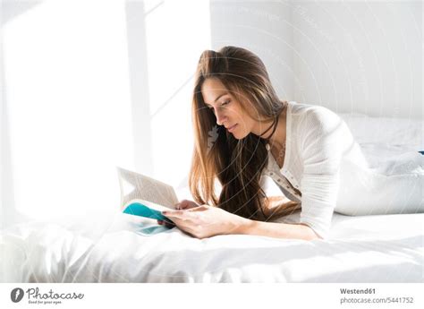 Young woman lying on bed reading book - a Royalty Free Stock Photo from ...