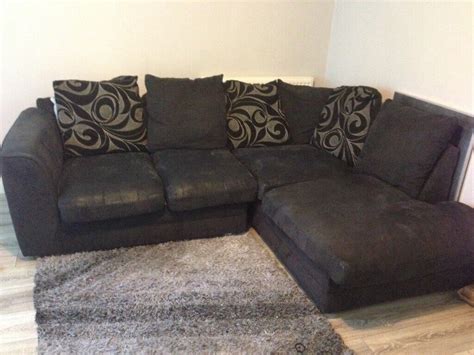 Black corner sofa with scatter cushions.few small holes on seat ...