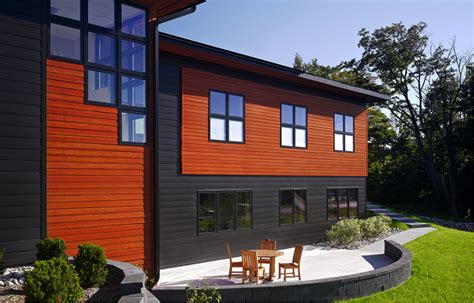 a house with two chairs and a table in front of it on the grass area