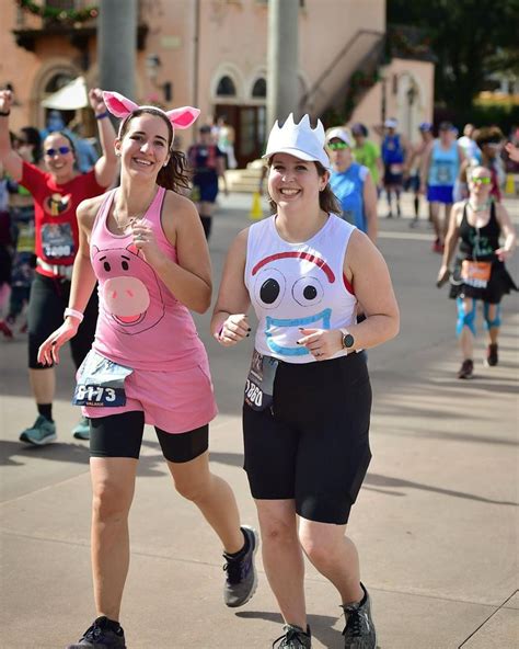 two women in costumes running down the street with other people behind ...