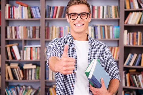 He loves studying. Handsome young man holding books and showing his ...