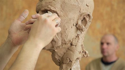 Sculptor modelling sculpture adjusting face details head made of clay ...