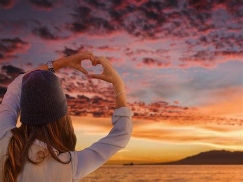 Free Photo | Back view woman making heart-shaped hands on a sunset