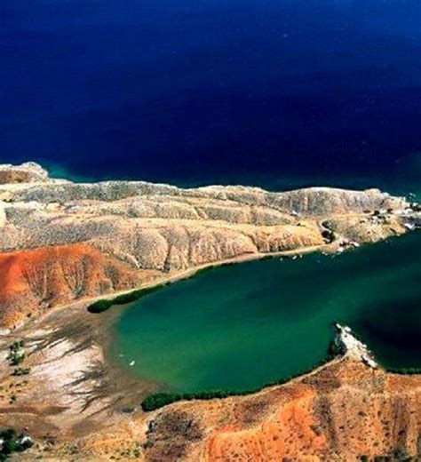 an aerial view of a lake surrounded by hills and cliffs in the ocean ...