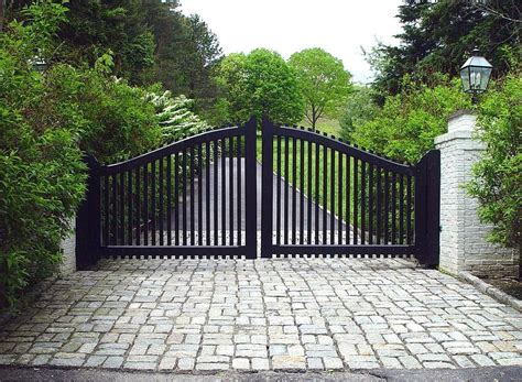 A transitional-style driveway gate features the arch and pickets of a ...