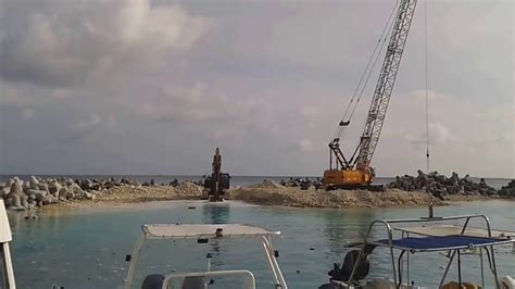 An excavator and crane in the breakwater offshore - YouTube