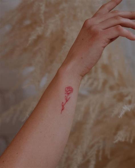 Fine line style red rose tattoo located on the wrist.