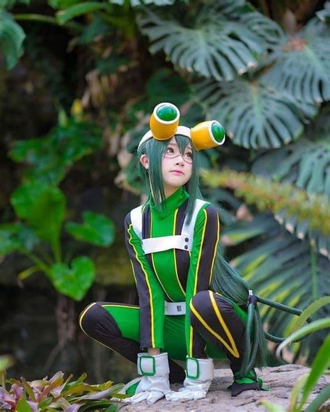 a woman with green hair is sitting on a rock in front of plants and trees