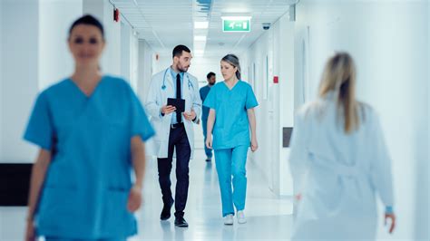 Surgeon and Female Doctor Walk Through Hospital Hallway, They Consult ...