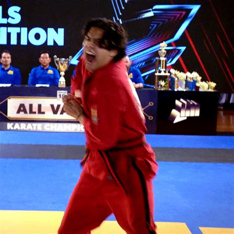 a man in a red outfit is on a blue mat and has his mouth open