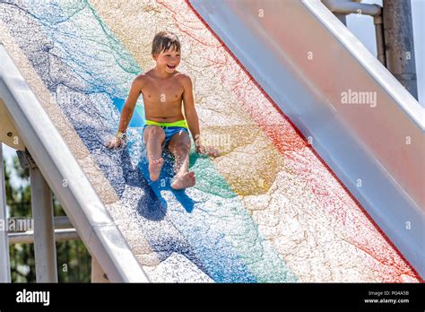 A happy boy on water slide in a swimming pool having fun during summer ...