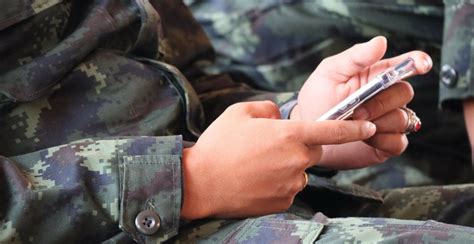 Close-up of military person in uniform holding a mobile device training ...