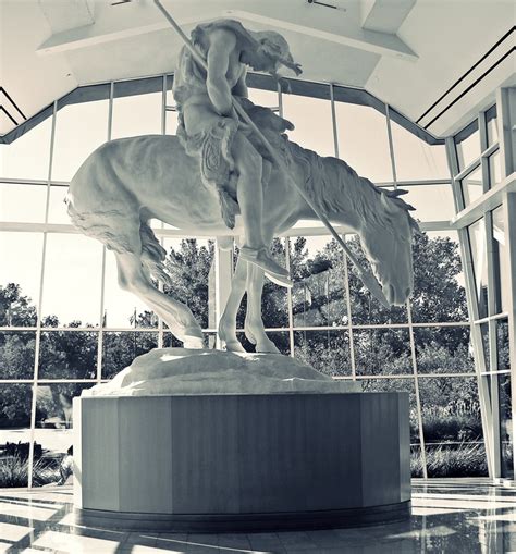 a black and white photo of a statue of a man riding a horse in front of ...