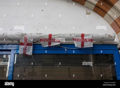 Dystopian detail of three torn English flags above the window of a ...