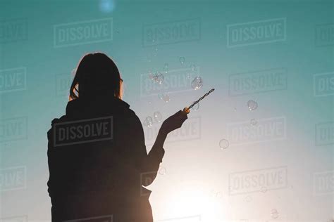 Silhouette of a woman waving bubble wand - Stock Photo - Dissolve