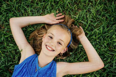 Close up portrait of smiling Caucasian girl laying on grass - Stock ...