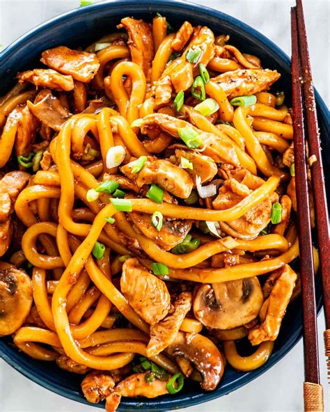 overhead shot of hoisin chicken udon noodles in a blue bowl garnished ...