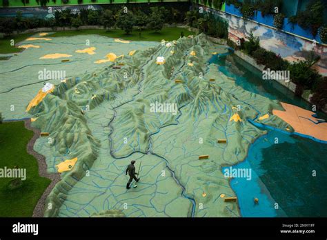 Staff member walks across a giant relief map of Colombia at Parque ...