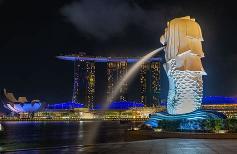 Skyline of Singapore business district at night with Merlion Statue. I ...