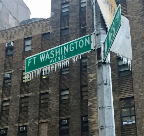 two street signs on a pole in front of a tall building with icicles ...