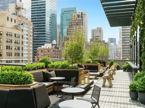 an outdoor patio with tables, chairs and potted plants on the roof of a ...