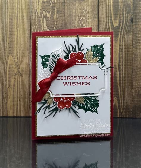 a christmas card with holly leaves and red ribbon on the front, sitting ...