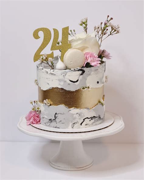 a white cake with gold numbers and flowers on top is sitting on a ...