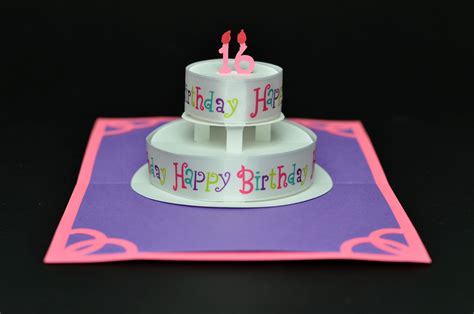 two tiered birthday cake sitting on top of a purple and pink card