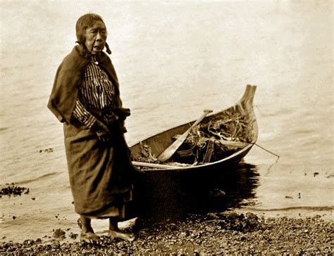 Elderly Coastal Salish woman standing next to her canoe. Photograph ...