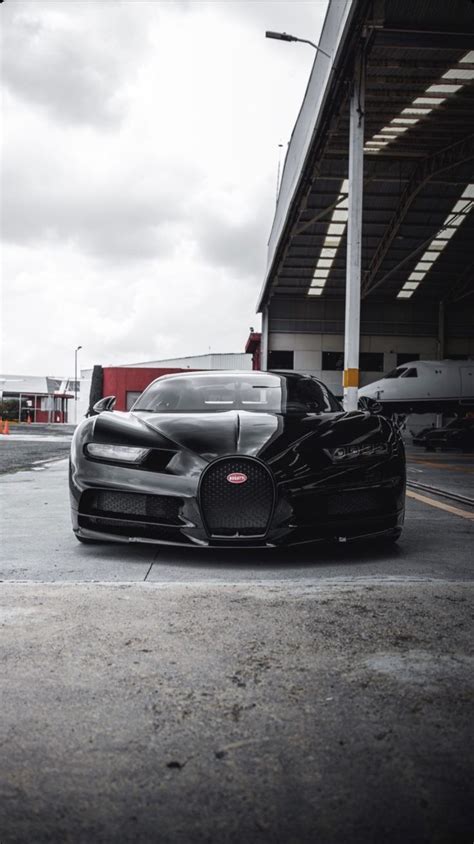 a black bugatti parked in front of a building next to a parking lot