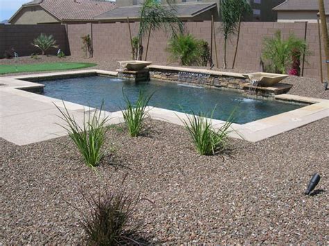 a small pool in the middle of a graveled area with plants and rocks ...