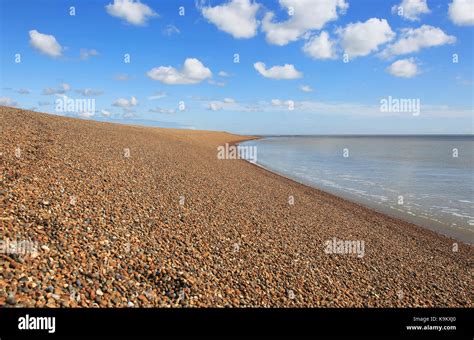 Steep beach profile sediment calm water blue sky white clouds landscape ...