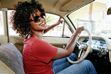 Mixed race woman driving vintage car - Stock Photo - Dissolve