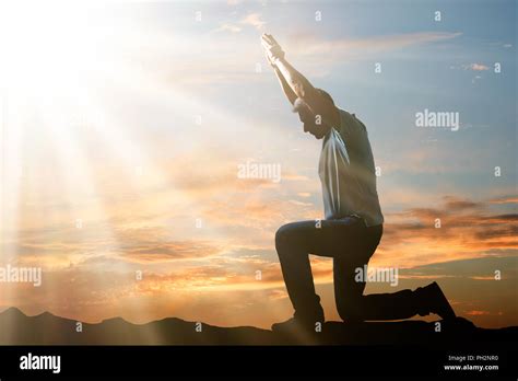 Side View Of A Man Kneeling And Praying Against Cloudy Sky At Sunset ...