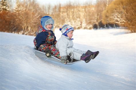 Two joyful child sledding down the hills in a winter day. — Manchester ...