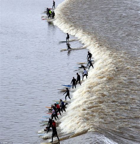 Riding the 20 MILE wave: Surfers pictured at sunrise cruising on the ...