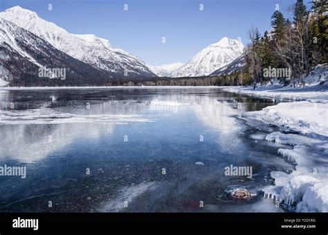 Montana Lake in Winter: Snow covered mountains reflect from the icy ...