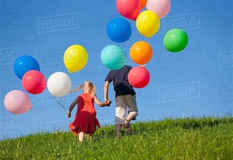 Children with colorful balloons in grass - Stock Photo - Dissolve