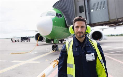 Portrait of airport ground crew standing on runway at airport terminal ...