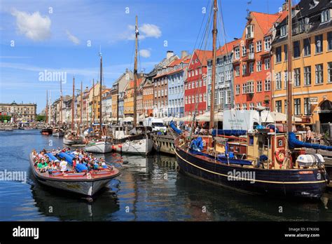 Tourists on Copenhagen canal tour boat with old boats moored in front ...