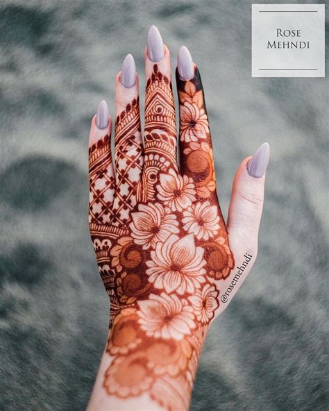 a woman's hand with hendi on it and flowers painted on the palm