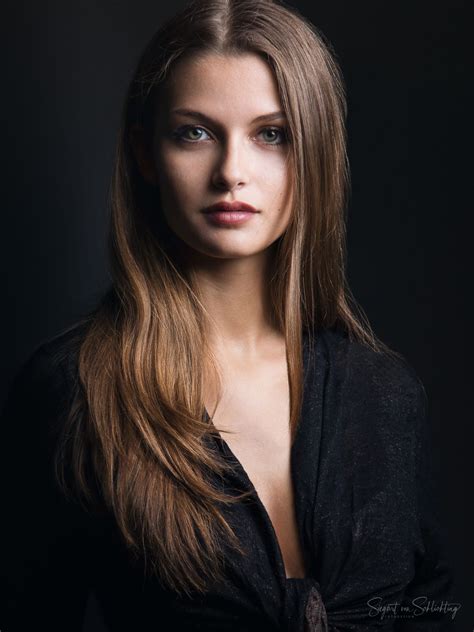 a woman with long hair and blue eyes posing for a photo in front of a ...